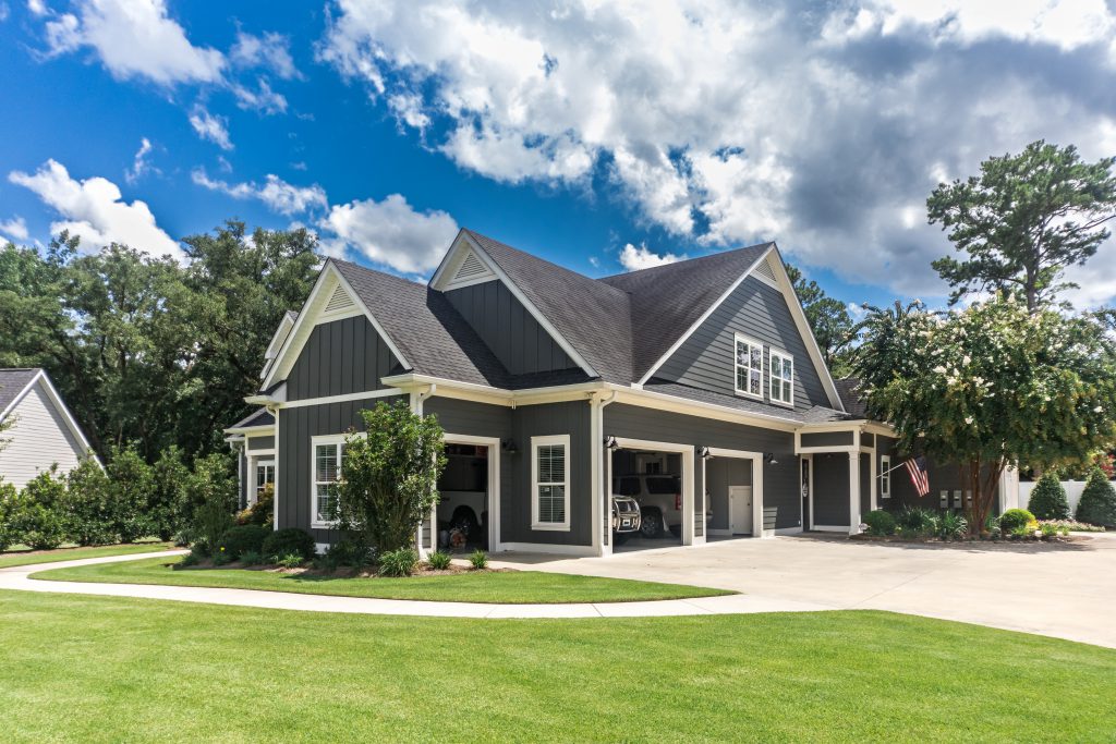 The side view of a large gray craftsman new construction house with a landscaped yard
