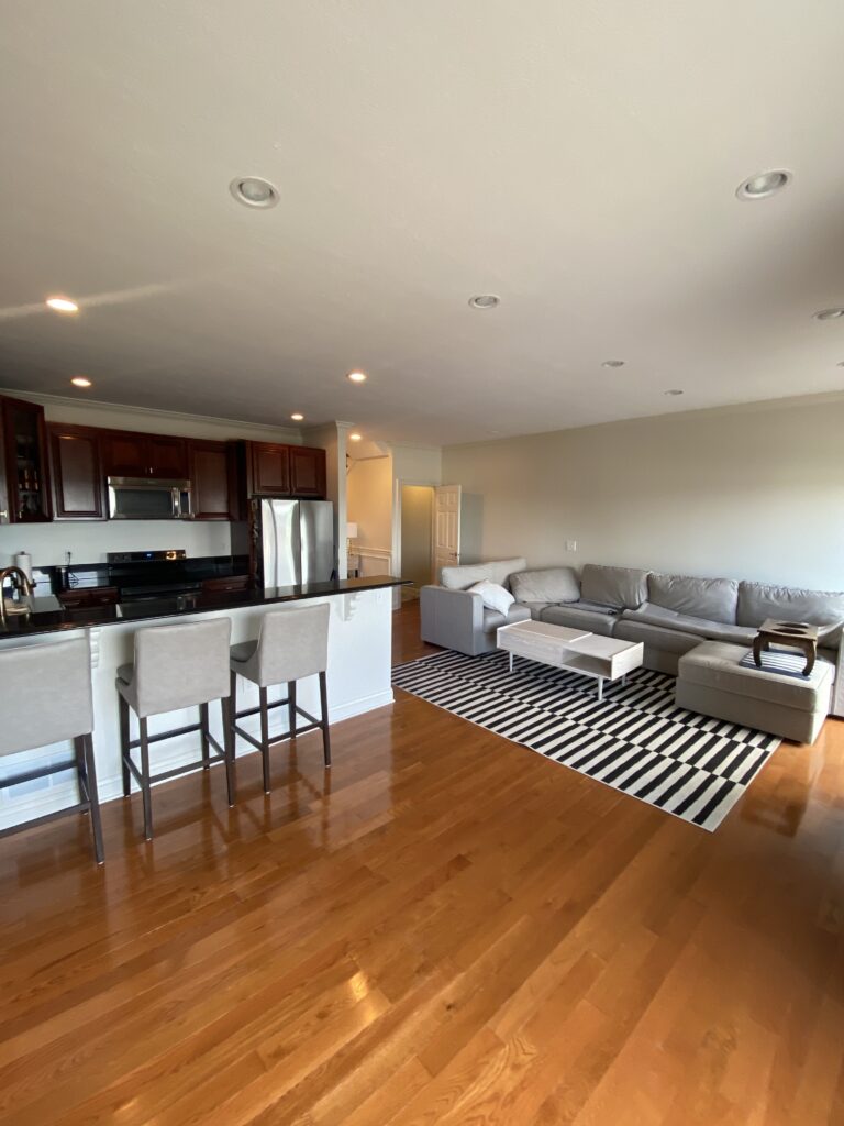 A picture of a newly painted Livingroom and Kitchen Area using neutral colors. It shows some sofa and other kitchen furniture