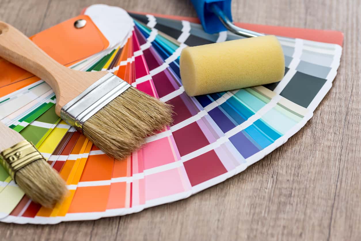 Paint brushes on colour swatch, wooden table background Best Interior Paint Colors -swatches and brushes